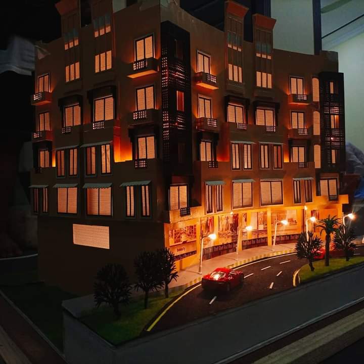 Physical scale model of the Business Center at Riveria, Bahria Phase 7, lit at night with shops at ground level and a road in front