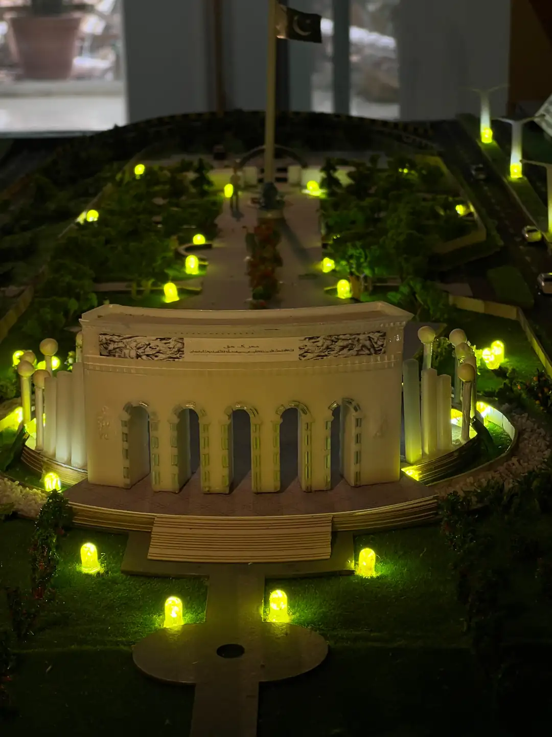 Illuminated physical model of the Marka-e-Haq Pakistan monument with its arched facade, raised plaza and garden lights